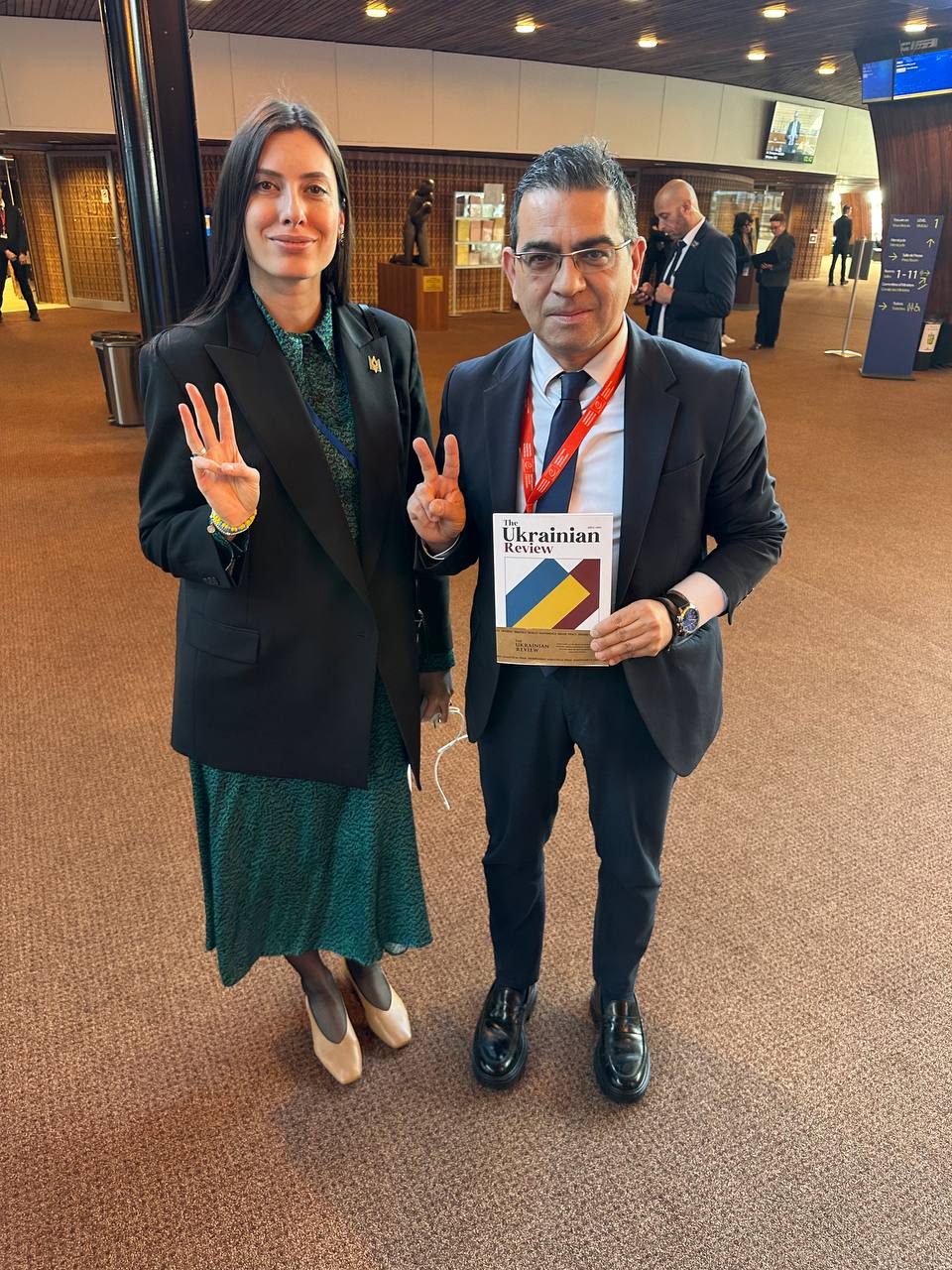 Mariia Mezentseva-Fedorenko (Ukraine) and Georgios Stamatis (Greece) holding The Ukrainian Review at the PACE session, April 10, 2025