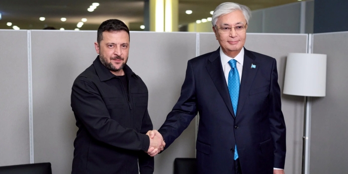 President of Ukraine Volodymyr Zelenskyy and President of Kazakhstan Kassym-Jomart Tokayev shake hands against a neutral grey background during their official meeting