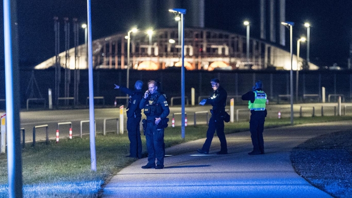 Danish police officers stand at night at Copenhagen Airport after drone incidents, ensuring security and controlling access near the terminals