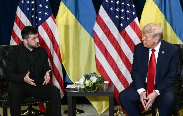 Ukrainian President Volodymyr Zelenskyy and U.S. President Donald Trump sit side by side during a meeting at the UN General Assembly in New York, with the U.S. and Ukrainian flags displayed prominently behind them