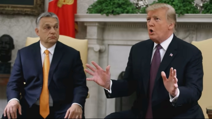 In the photo (Mark Wilson/Getty Images), U.S. President Donald Trump and Hungarian Prime Minister Viktor Orbán are seen in mid-conversation. Both men are seated close to each other at a table, leaning slightly forward as if engaged in a private discussion. Trump is gesturing with one hand, while Orbán listens attentively.