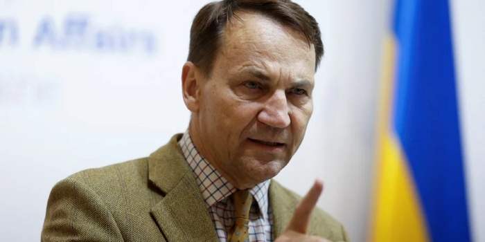 Polish Foreign Minister delivers a firm statement during a press event, pointing his finger in emphasis