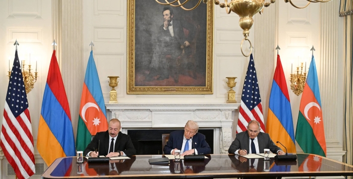 Leaders of Azerbaijan, the United States, and Armenia sign a peace agreement during an official ceremony, with their national flags displayed in the background