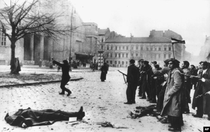 Historic black-and-white AP photograph from the 1956 Hungarian Revolution showing a killed person lying on the street amid the uprising