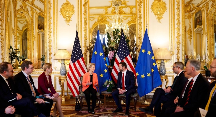 An illustrative photo showing European Union and United States leaders sitting together at a high-level meeting, with EU and U.S. flags in the background, capturing diplomacy, negotiations and transatlantic cooperation.