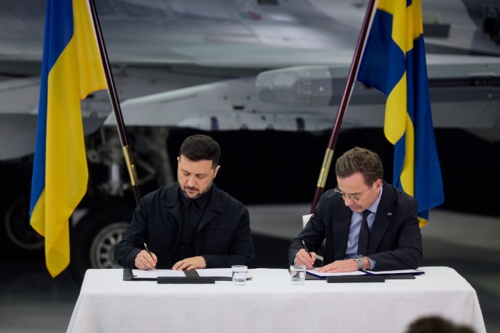 President of Ukraine Volodymyr Zelenskyy and Prime Minister of Sweden Ulf Kristersson are depicted while signing a list on the Gripen background