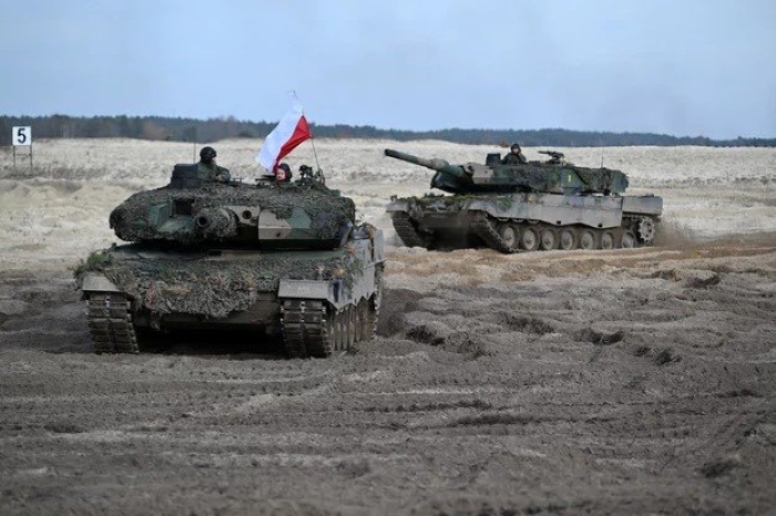 **SEO description:**Polish Leopard 2 tanks during military exercises on a sandy training ground. The image shows modern armored vehicles of the Polish Army, equipped for NATO maneuvers and defense operations in Europe. The Polish flag is visible on one of the tanks, symbolizing national defense readiness and allied cooperation.