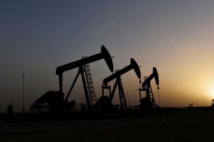 Silhouettes of oil pump jacks operating at sunset in a desert oil field. The image captures the energy industry and global oil production concept, highlighting fossil fuel extraction and petroleum economy themes.