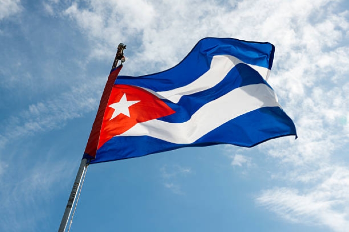 Cuban flag is depicted on the background of blue sky with clouds