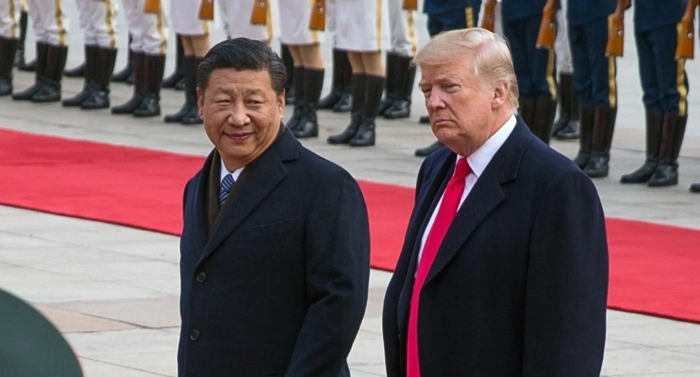 Donald Trump and Xi Jinping stand side by side during an official ceremony with military guards in the background, symbolizing diplomatic relations between the United States and China.