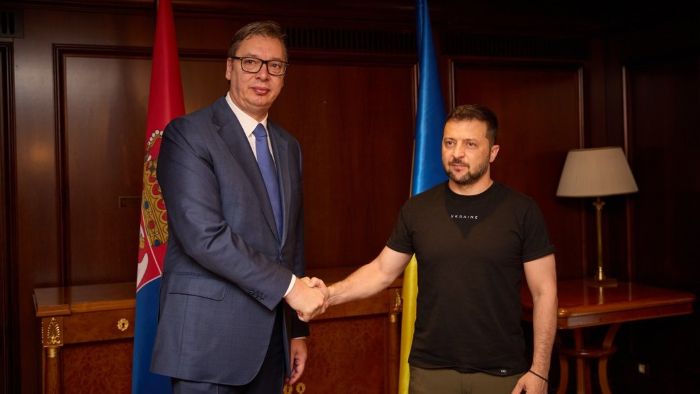 Ukrainian President Volodymyr Zelenskyy meets Serbian President Aleksandar Vučić during an official visit, symbolizing diplomatic dialogue between Ukraine and Serbia. The leaders discuss cooperation, European integration, and regional stability. The photo captures a formal handshake in front of Ukrainian and Serbian flags.