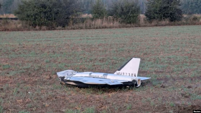 A damaged Russian drone lies in an open Polish field after crash-landing, with its tail section and serial markings still visible.
