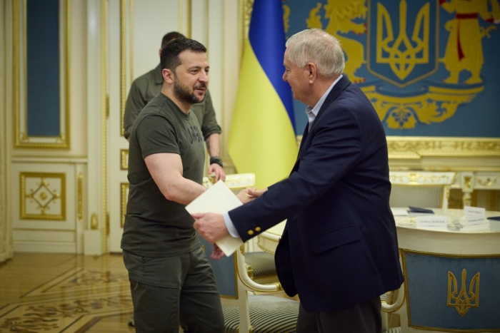US Senator Lindsey Graham and Volodymyr Zelenskyy are depicted shakind hands on the background of Ukrainian flag