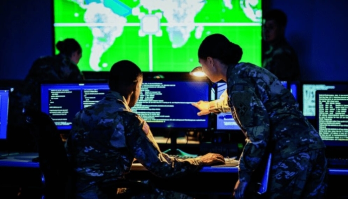 A team of military cyber-defense specialists works in a high-tech operations center, analyzing real-time data on multiple screens against the backdrop of a global digital map.