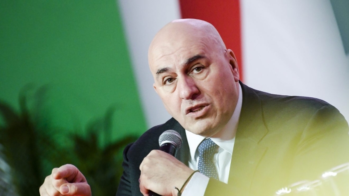 Italy’s defence Minister Guido Crosetto is depicted speaking on the background of Italian flag