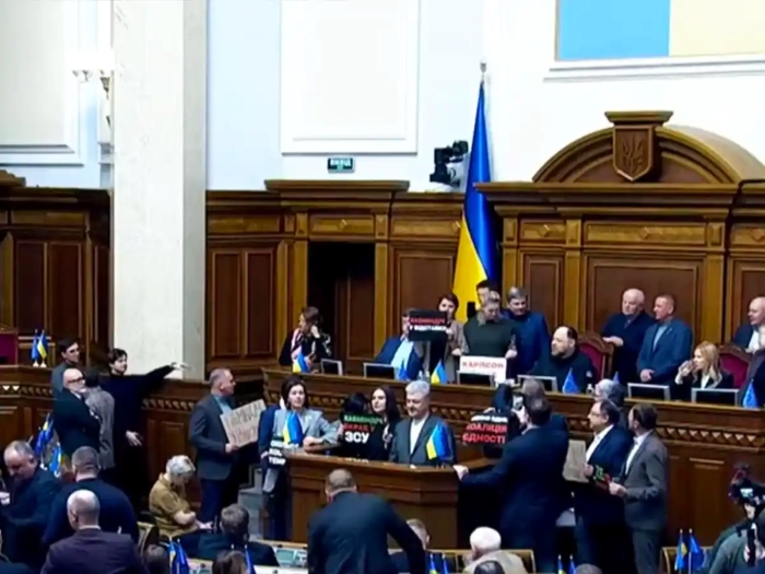 The picture shows Rada blocking the podium, demanding the resignation of the government on November 18, 2025. Some governers stay with posters.