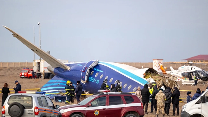 Emergency responders and investigators work at the crash site of a damaged passenger AZAL aircraft lying broken on the ground