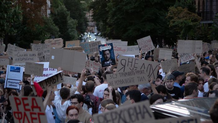Large street protest with a dense crowd of people holding handmade cardboard signs during a public demonstration in Ukraine