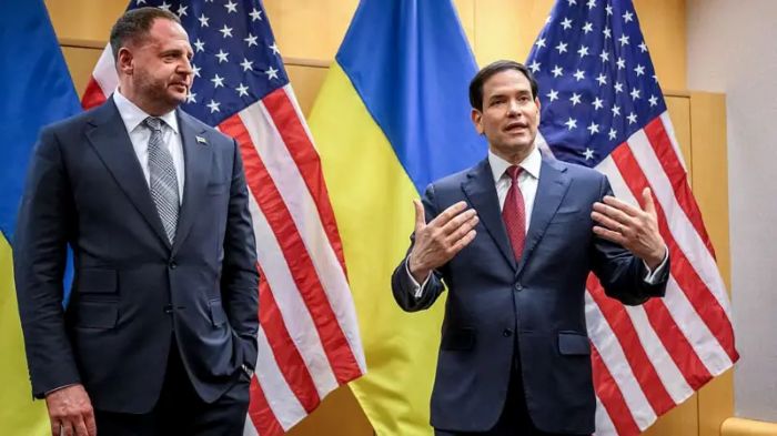 The picture shows Andrii Andrii Yermak and Marco Rubio standing in front of national flags