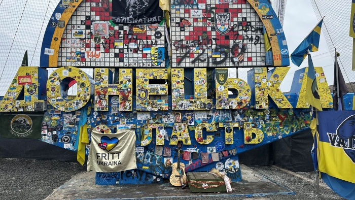 A sign at the entrance to the Donetsk region on 3 February 2025 covered with unit patches, symbols, and messages of remembrance.