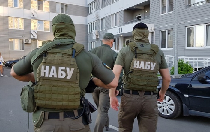 Ukrainian anti-corruption officers from NABU are shown conducting an operation in a residential area.
