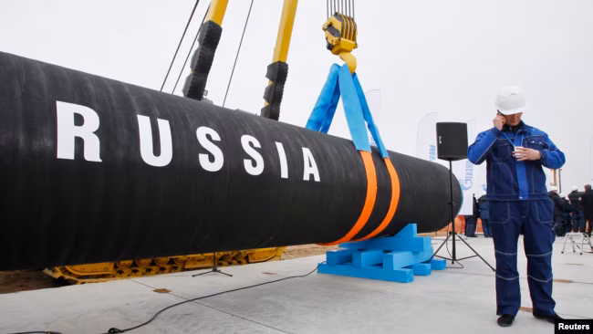 A Russian construction worker speaks on a mobile phone in Portovaya Bay some 170 kms northwest from St. Petersburg, Russia, during a ceremony marking the start of Nord Stream pipeline construction, April 9, 2010 / Voice of America