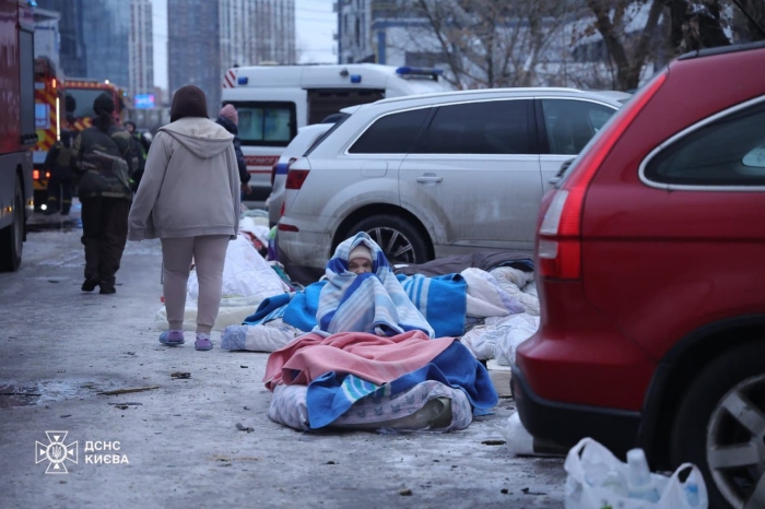 People in Kyiv seat outside on snow because of the attack on their residential building