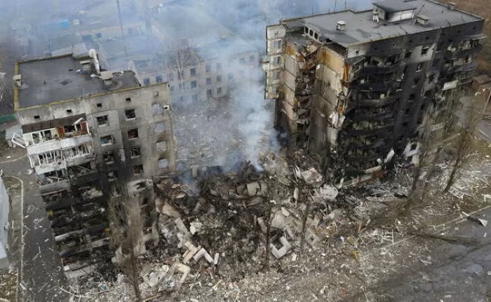 An aerial view of a heavily damaged residential building in Ukraine after a russian airstrike, showing collapsed structures, smoke rising from the ruins, and widespread destruction.