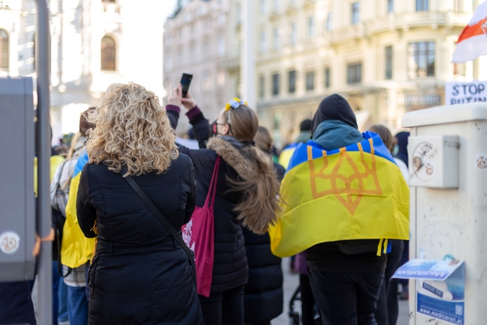 The picture shows people with Ukrainian flags on a Rally in Vienna