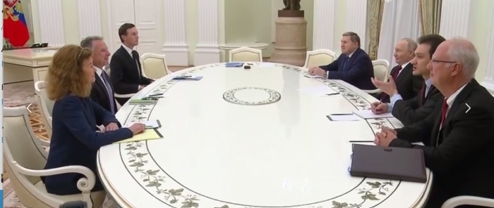A high-level diplomatic meeting between the U.S and Russia is taking place at a long oval table in an ornate government hall