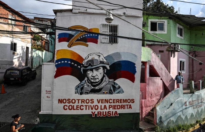 A political mural depicting Vladimir Putin in military gear painted on a residential building in Venezuela, accompanied by Venezuelan and russian flags and the Spanish slogan “Nosotros venceremos” (“We will win”).