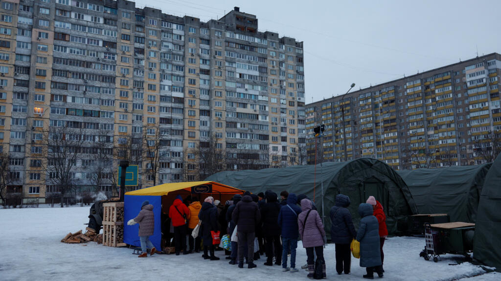 Residents receive hot food from volunteers near tents at the checkpoint