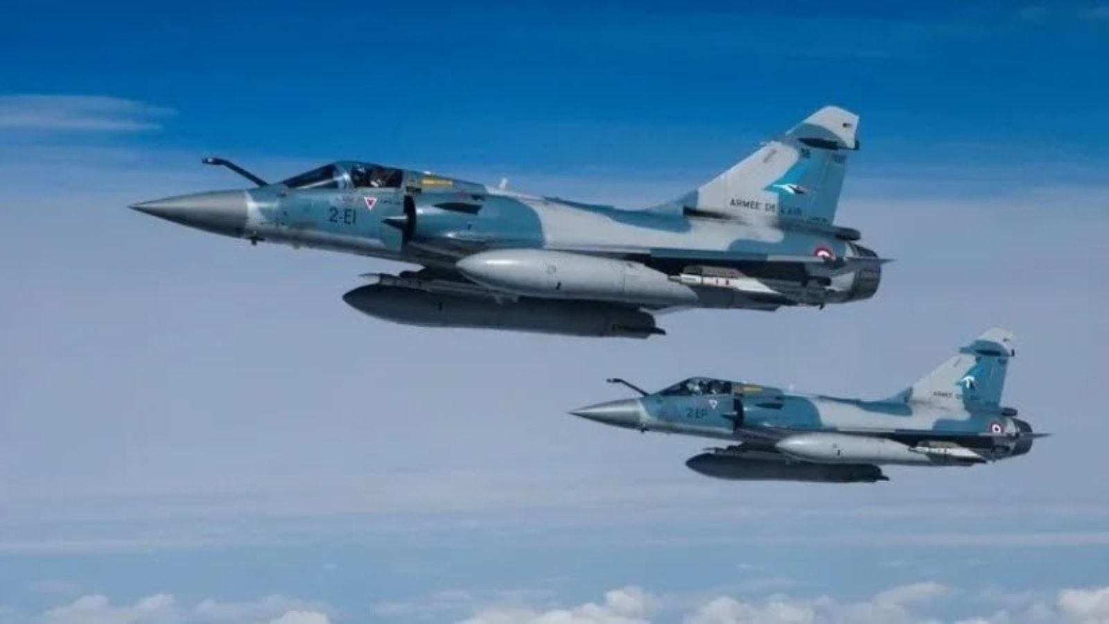 Two French Mirage 2000-5F fighter jets flying in formation above the clouds.