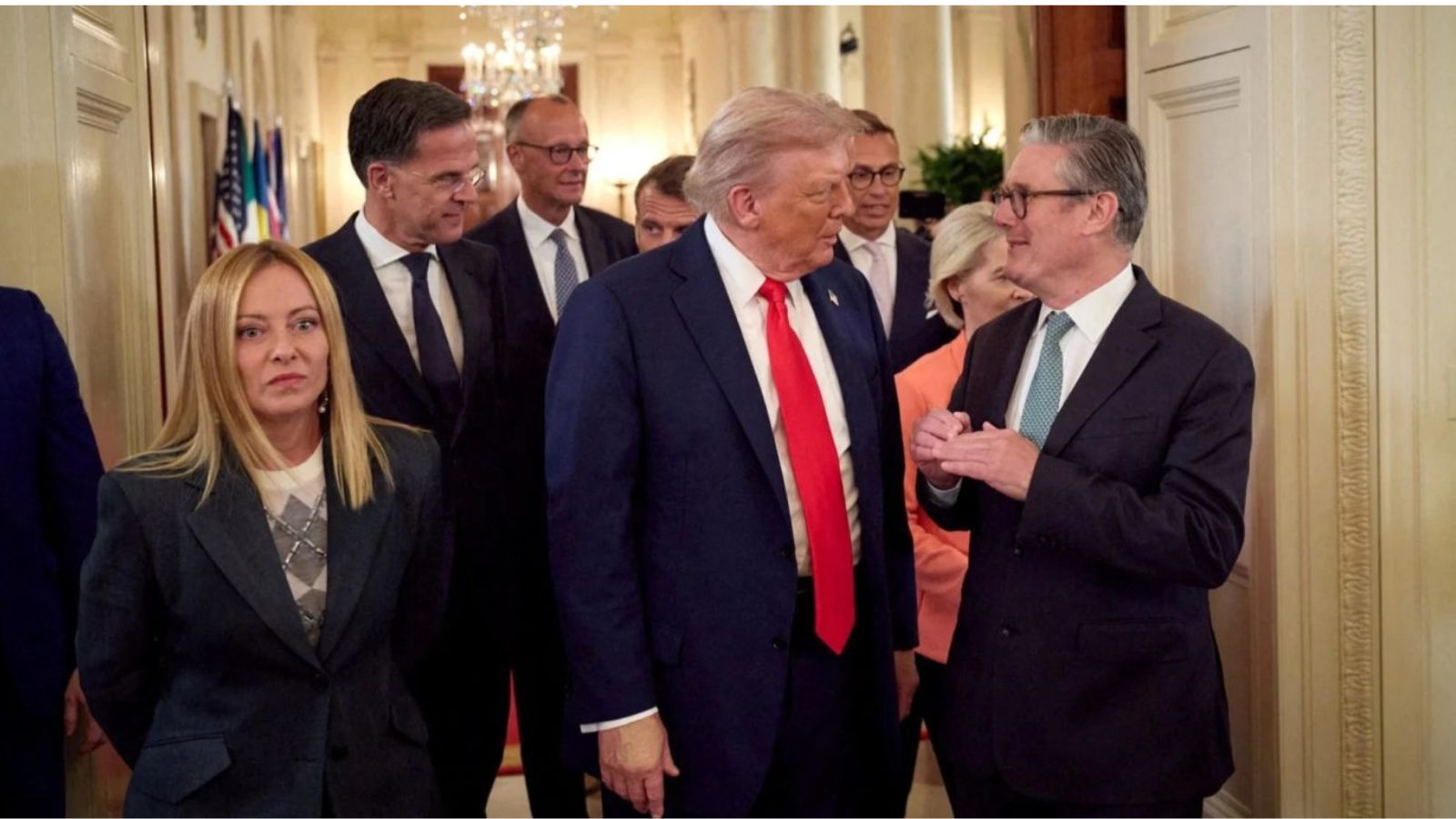 Donald Trump talking to Keir Starmer in a White House hallway, surrounded by other European leaders, including Giorgia Meloni.