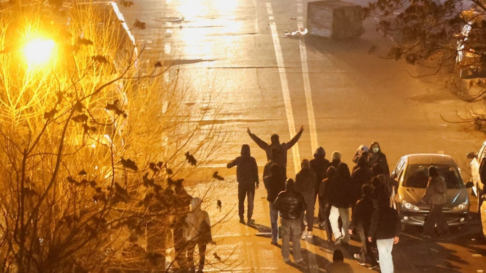 Група людей на нічній вулиці Тегерана під час акції протесту; один чоловік підняв руки з жестом перемоги.