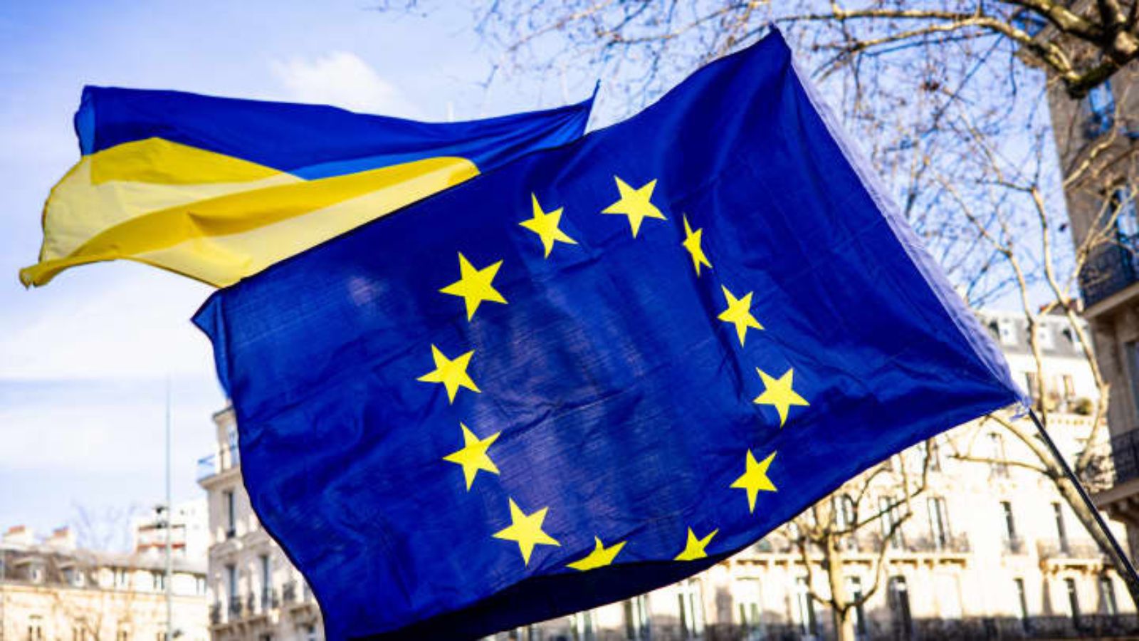People at a rally in Paris holding large Ukrainian and EU flags in a show of support.