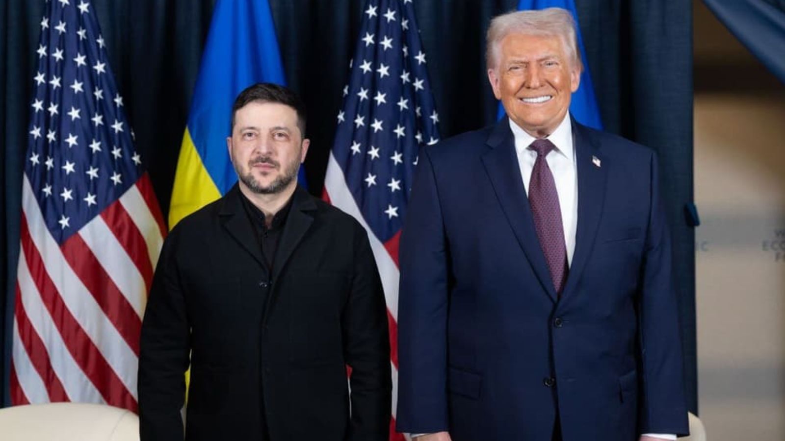 Ukrainian President Volodymyr Zelenskyy and U.S. President Donald Trump standing together in front of Ukrainian and American flags in Davos.