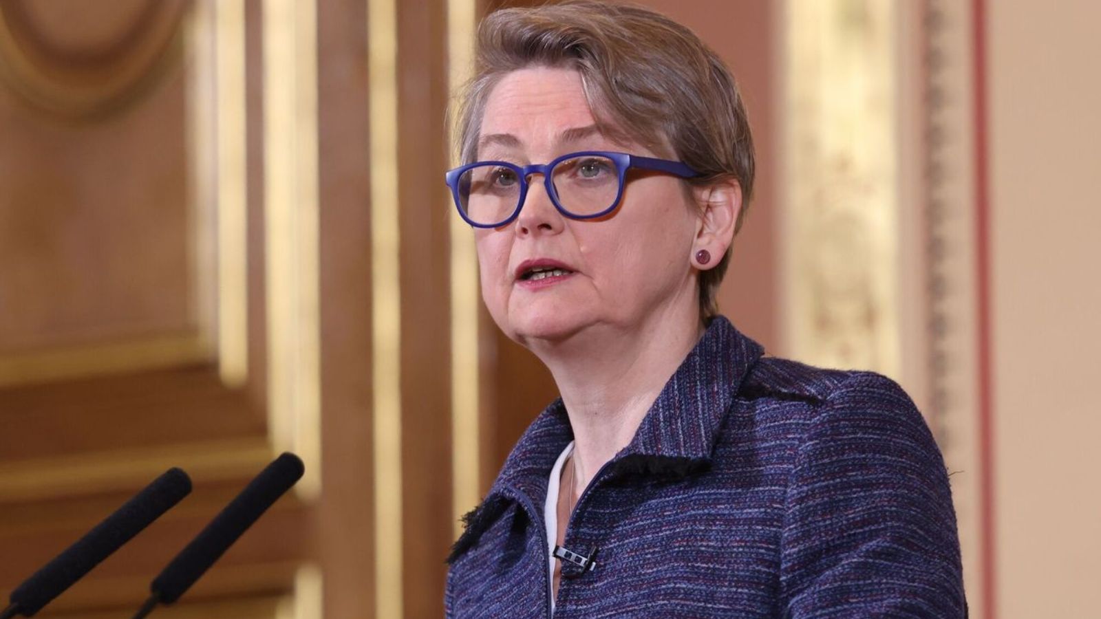 Портрет міністерки закордонних справ Великої Британії Іветт Купер в окулярах у синій оправі під час промови.