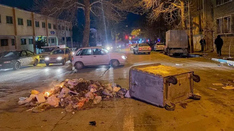 Burning debris and an overturned garbage container on the street during riots in Hamadan on January 1