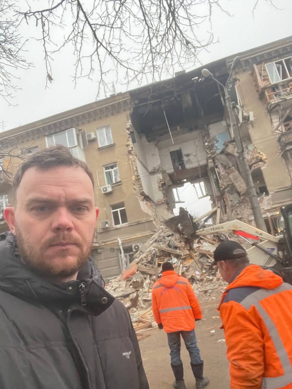 Portrait of Volodymyr Savchenko against the background of a damaged building in Odesa while documenting the consequences of the attack.