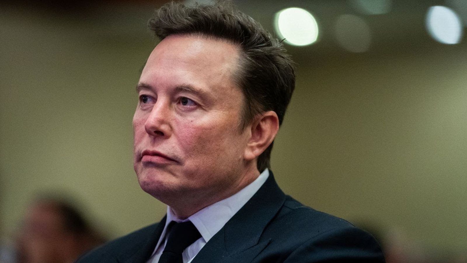 Close-up of American businessman Elon Musk, founder of SpaceX, wearing a dark suit against a neutral background.