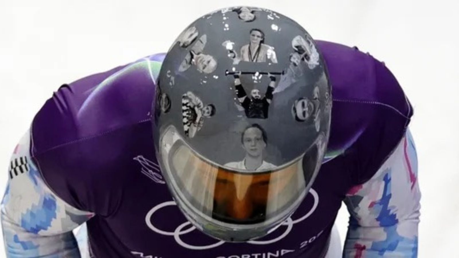 Ukrainian skeleton racer Vladyslav Heraskevych preparing for a run while wearing a helmet featuring photos of fallen athletes.