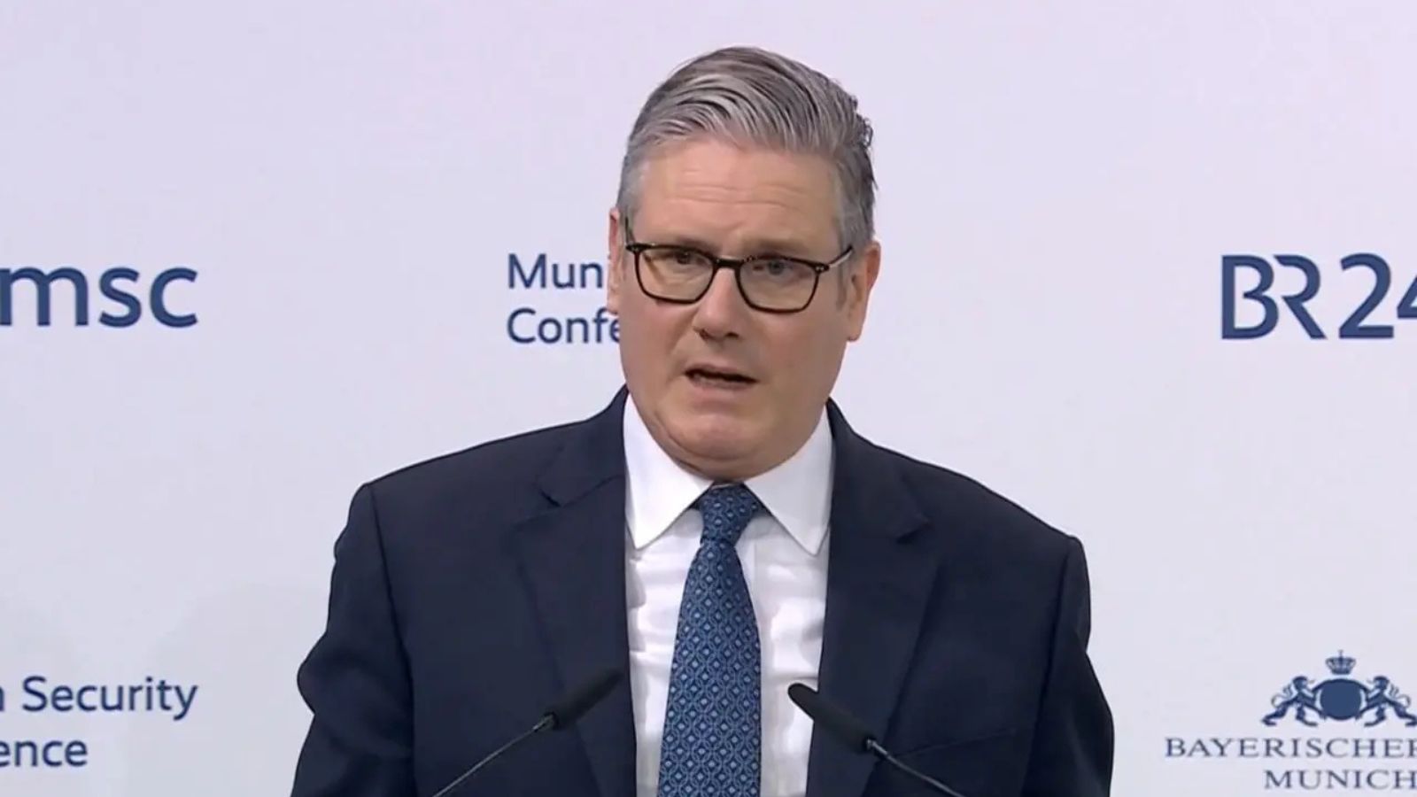 Close-up of Keir Starmer in a dark suit and blue tie during his speech at the conference.