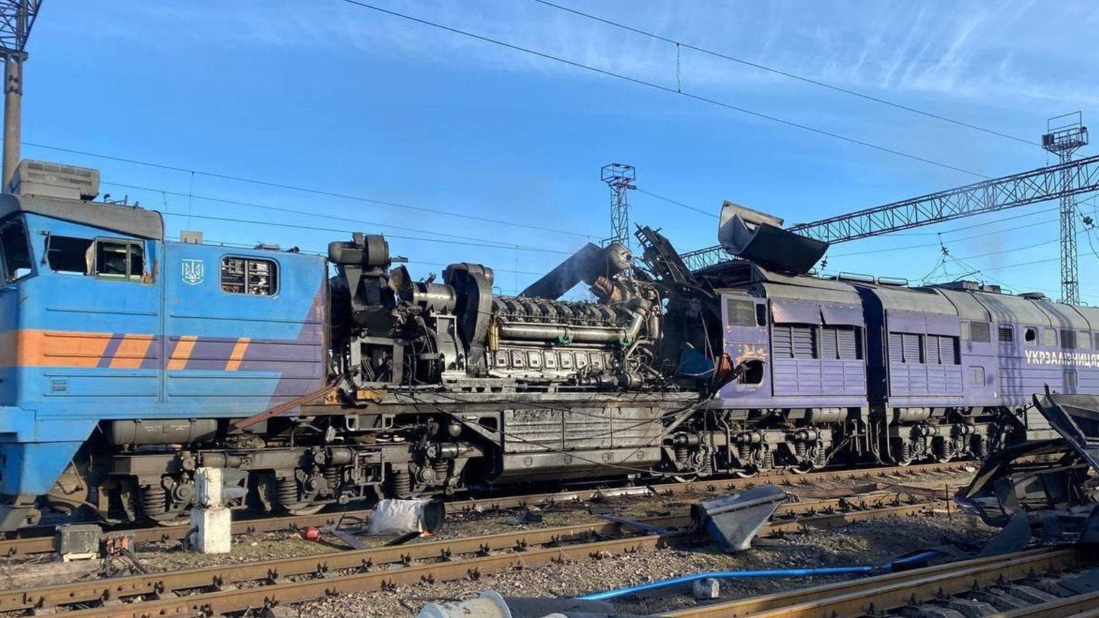 A heavily damaged blue railway locomotive with an exposed engine following an attack on railway infrastructure.