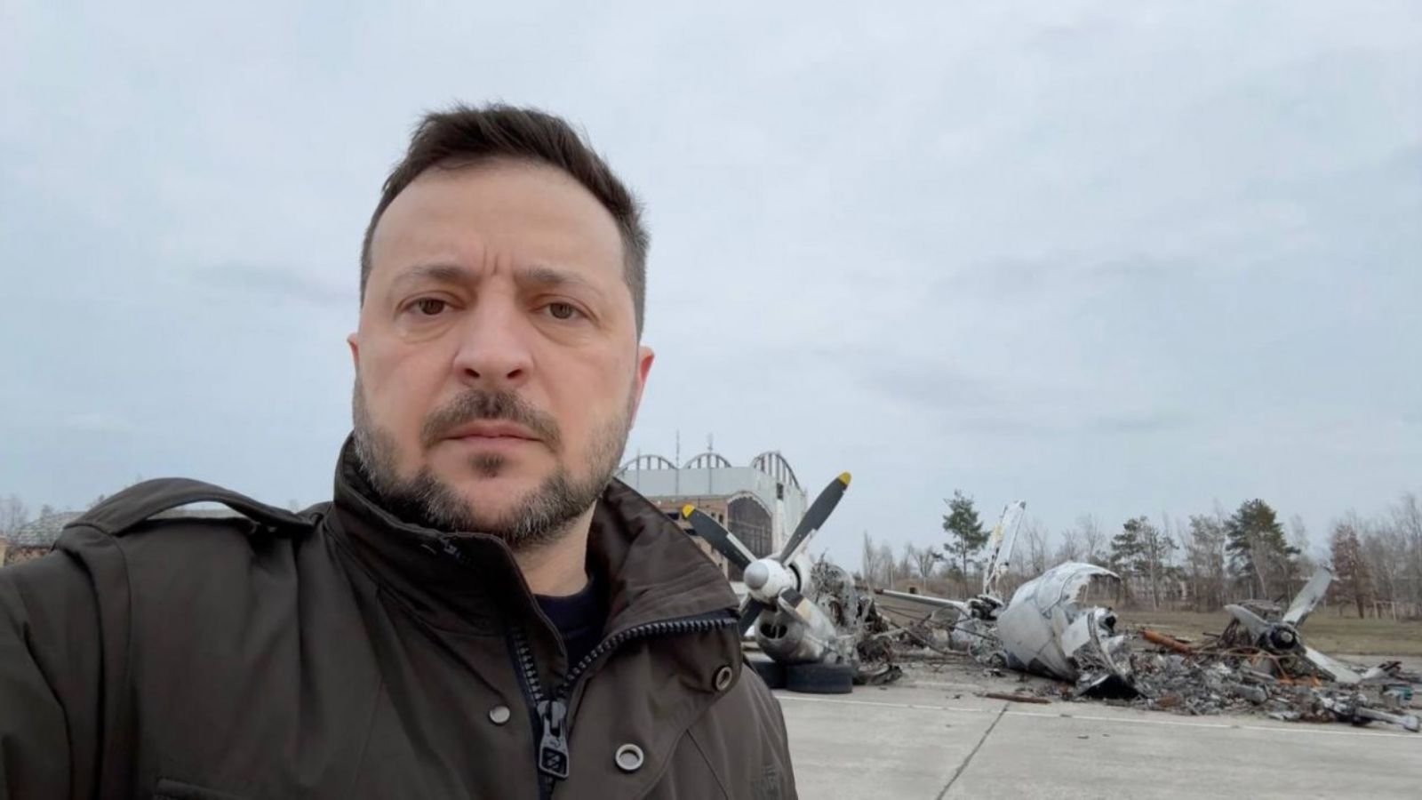 Volodymyr Zelenskyy against the backdrop of a destroyed aircraft and hangar at Hostomel airport on the second anniversary of the war