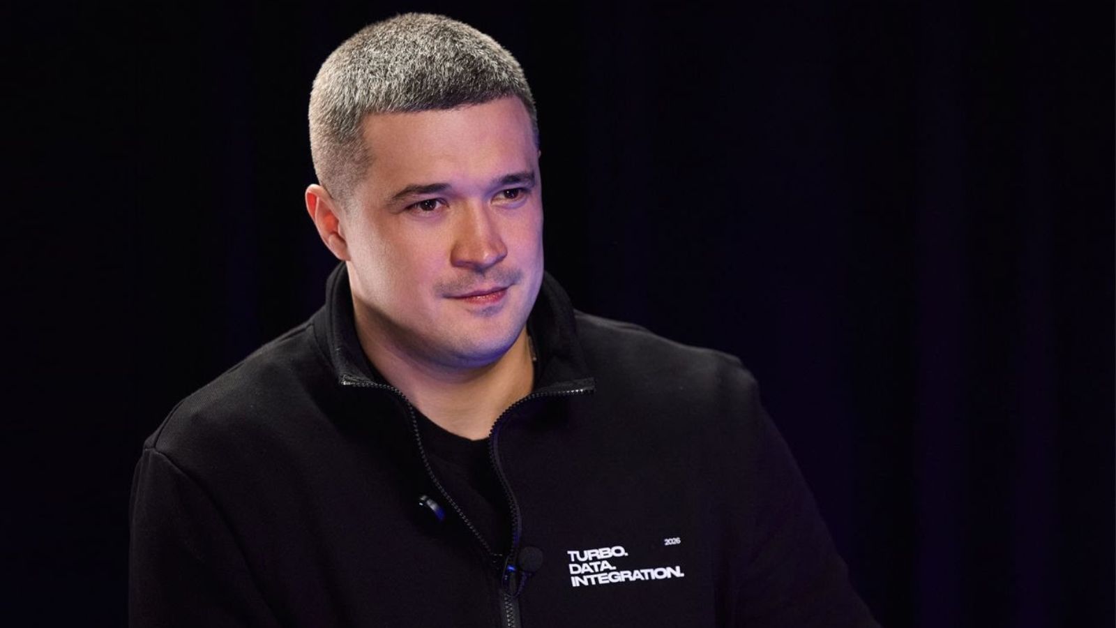 Portrait of Mykhailo Fedorov in black clothing during a business meeting.