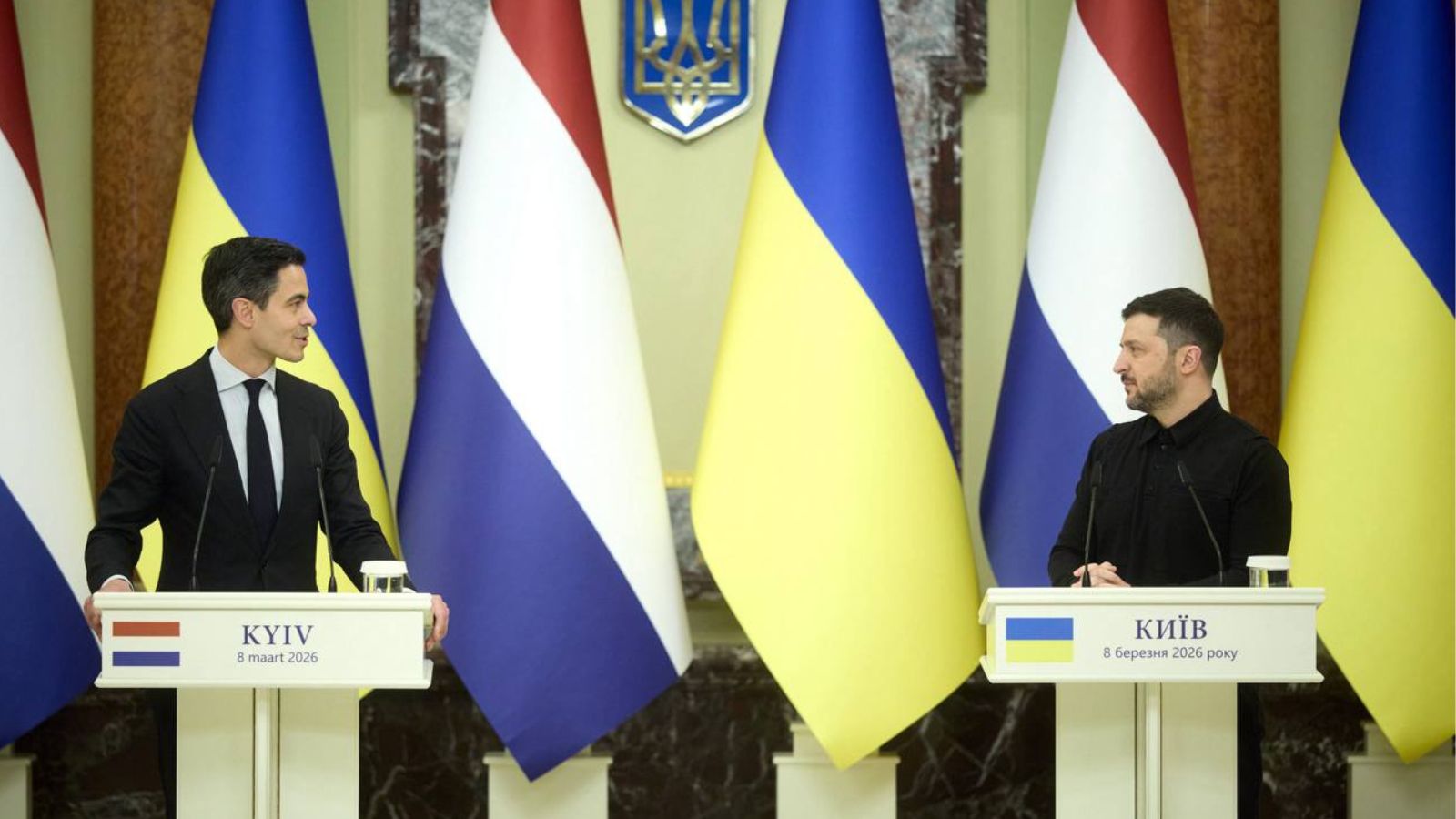 Володимир Зеленський та Роб Єттен стоять за трибунами під час спільної пресконференції у Києві. На задньому плані — прапори України та Нідерландів.