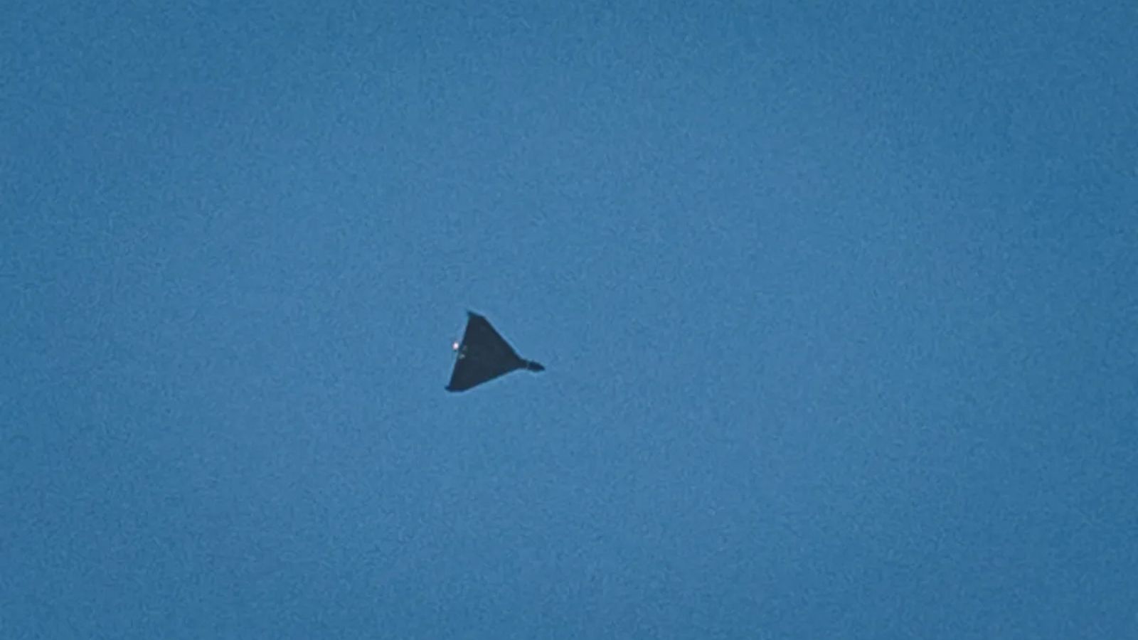 An Iranian-made Shahed kamikaze drone, triangular in shape, flies in a clear blue sky