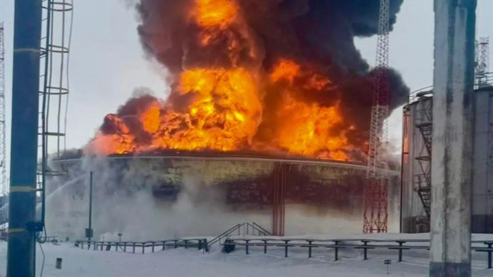 Large fire and black smoke rising above an oil facility