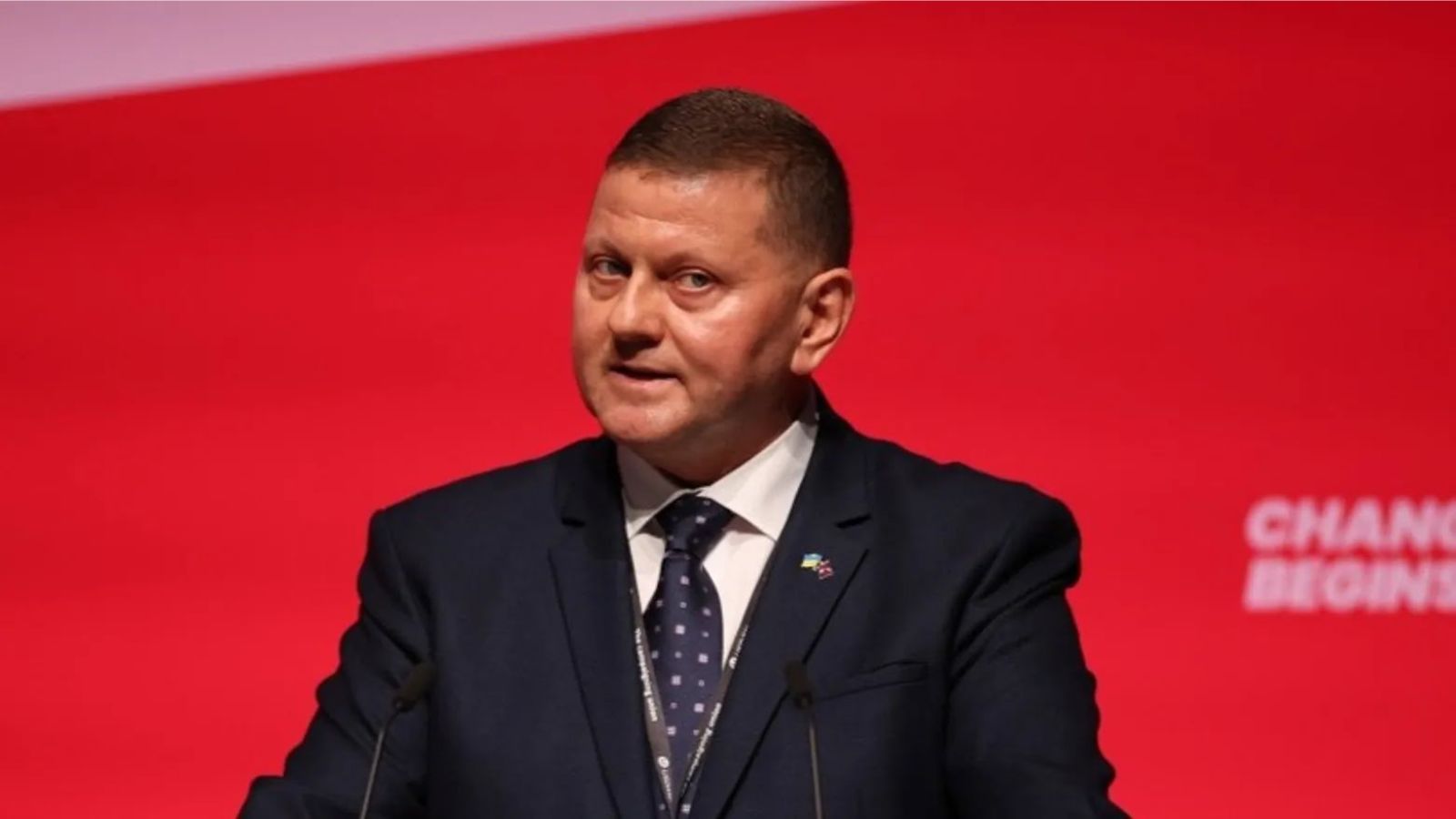 Valerii Zaluzhnyi speaking in front of a red banner with the words "Change Begins".